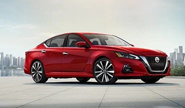 2023 Nissan Altima in red with city in background illustrating last year's 2022 model in Benton Nissan of Oxford in Oxford AL
